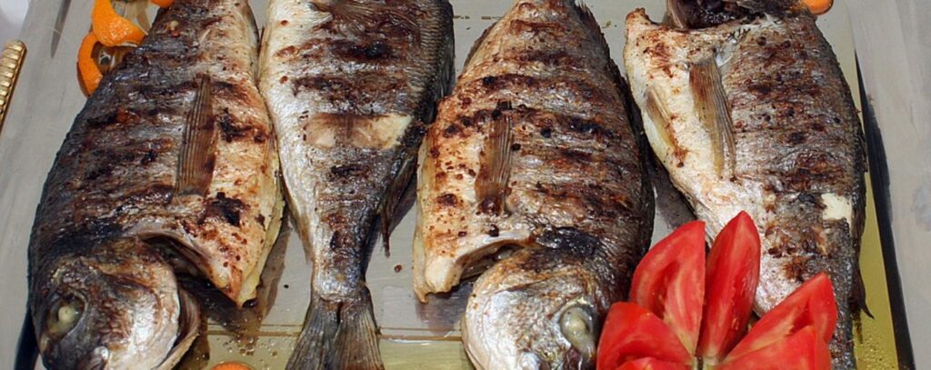 Whole grilled fish served with fresh tomato at a Caribbean restaurant